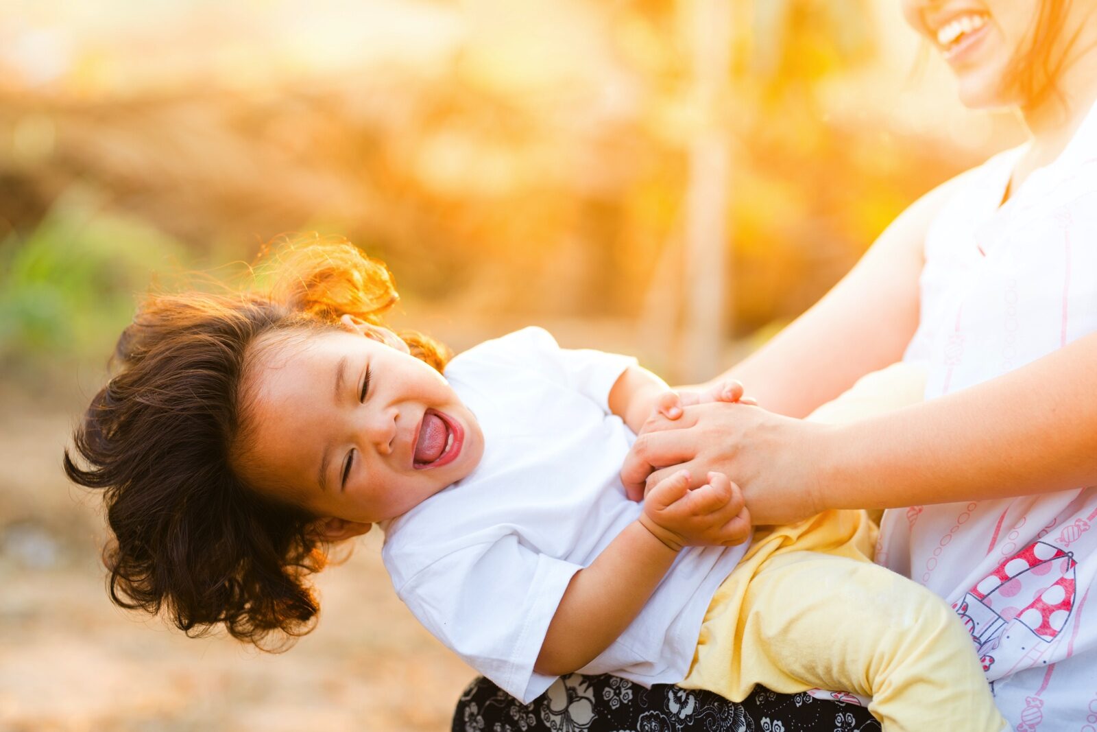 Laughing child leaning back on woman's knee