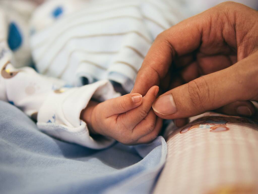 Close up of a mother's hand holding a baby's hand